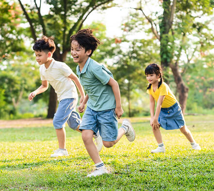 Children playing and running outdoors during student care activities at Joyful Explorers